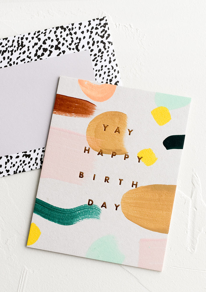 A birthday card with abstract painted pattern and text reading "YAY happy birthday".