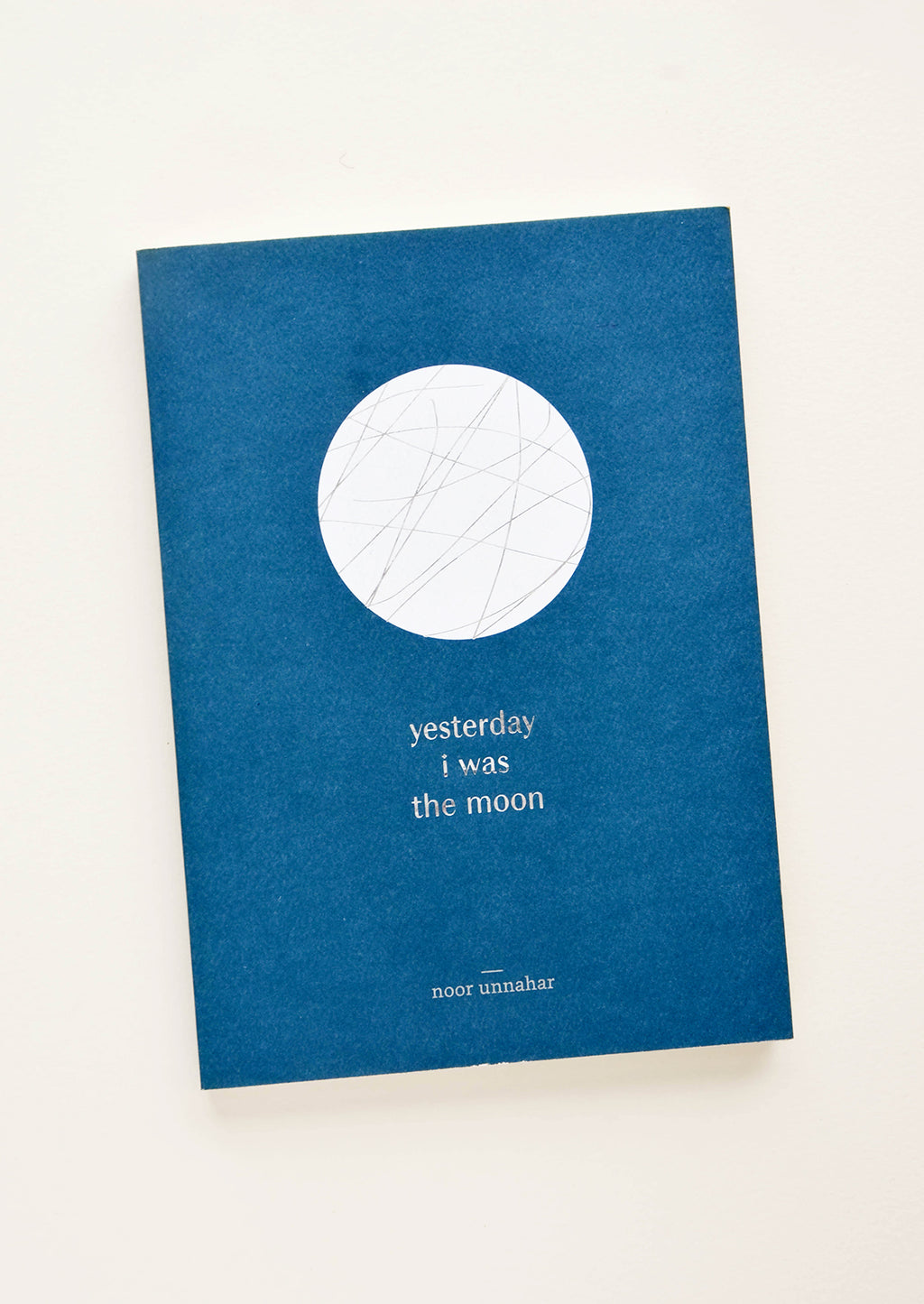 1: Softcover book in indigo blue with white moon print, silver title text