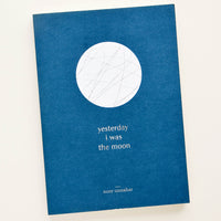 1: Softcover book in indigo blue with white moon print, silver title text