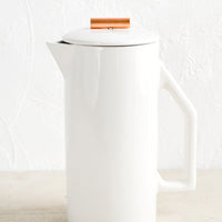 White Ceramic: A french press coffee maker made from white ceramic with a copper rod on lid.