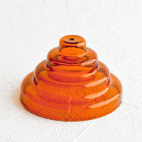 Amber: An incense holder made of glass in sculptural design with small hole at top, in amber.