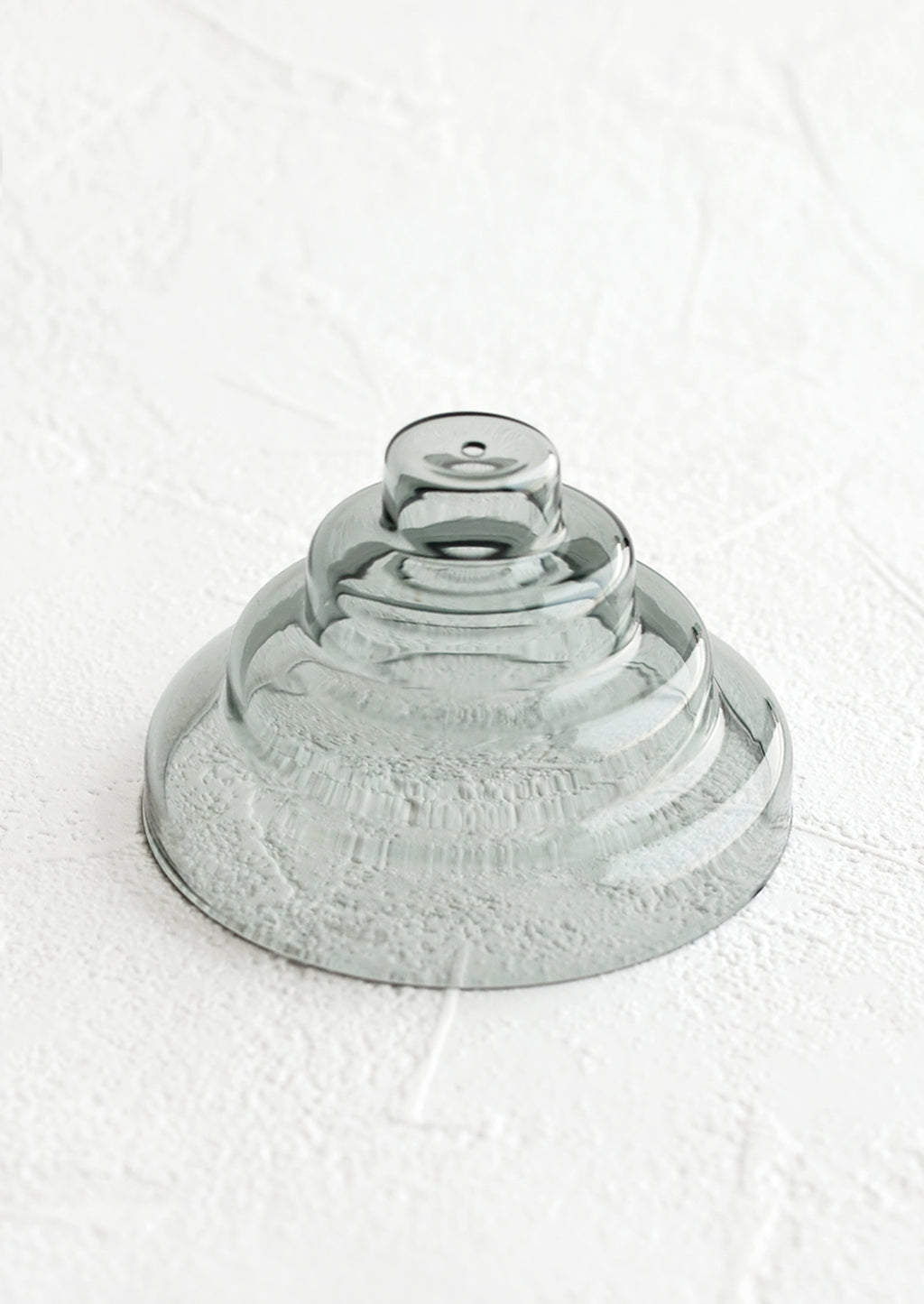 Grey: An incense holder made of glass in sculptural design with small hole at top, in grey.