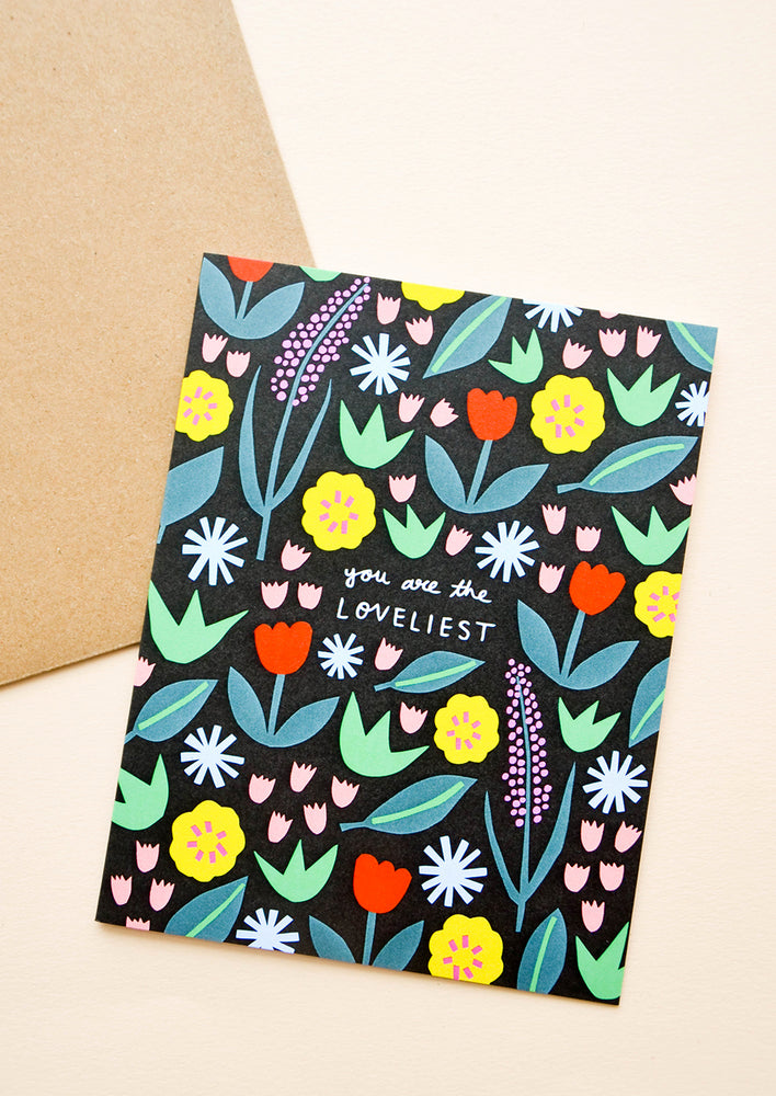 1: Greeting card with vibrant floral print atop black backdrop, text reads "You are the loveliest"