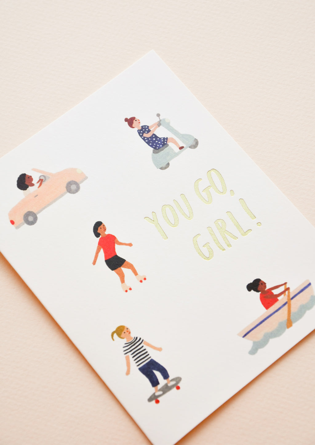 2: A greeting card with little illustrations of women in motion and the words "you go girl" in gold foil.