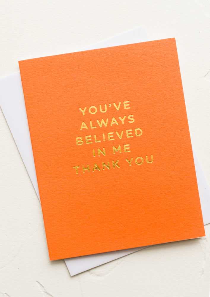 1: An orange greeting card with gold letters reading "You've always believed in me thank you".