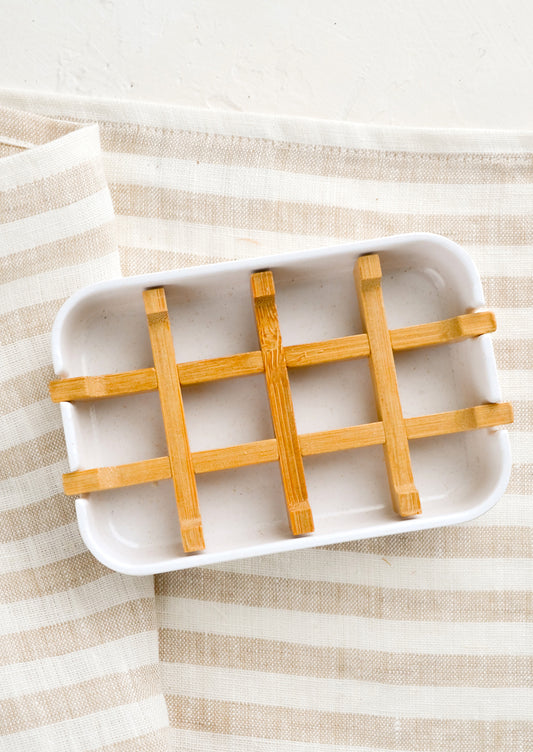 A white soap dish with built-in bamboo drainage tray.