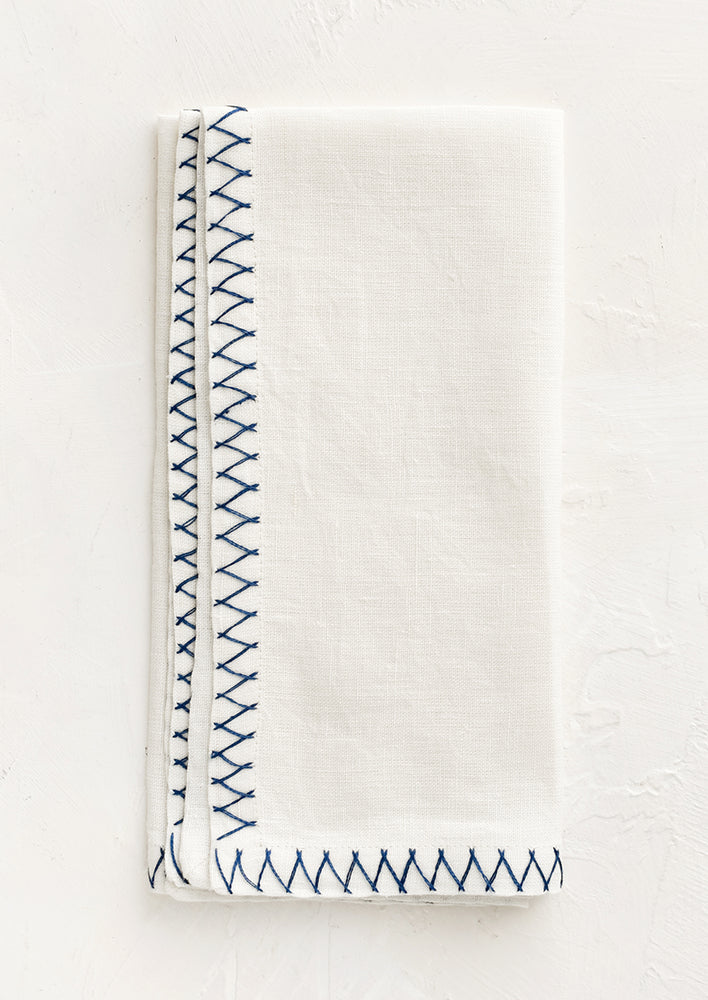 Marine Blue: A white linen napkin with blue embroidered zig zag border.