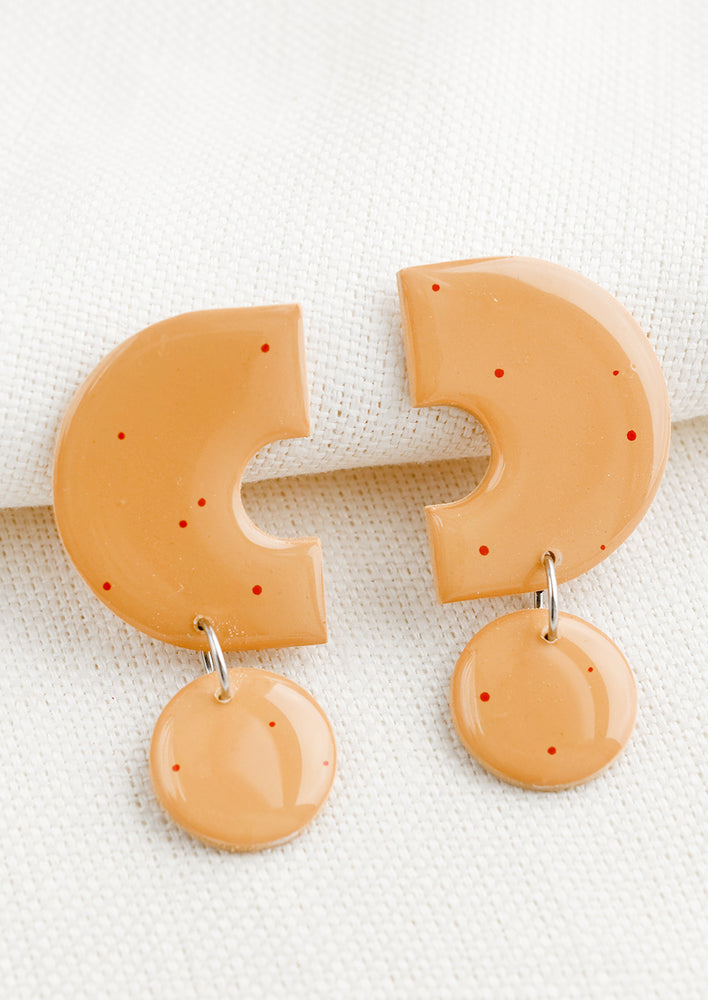 Peach: A pair of clay earrings with geometric shape in peach with red splatters.