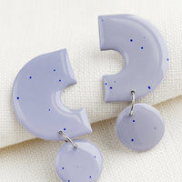 Lilac: A pair of clay earrings with geometric shape in purple with blue splatters.