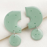 Seafoam: A pair of clay earrings with geometric shape in seafoam with green splatters.